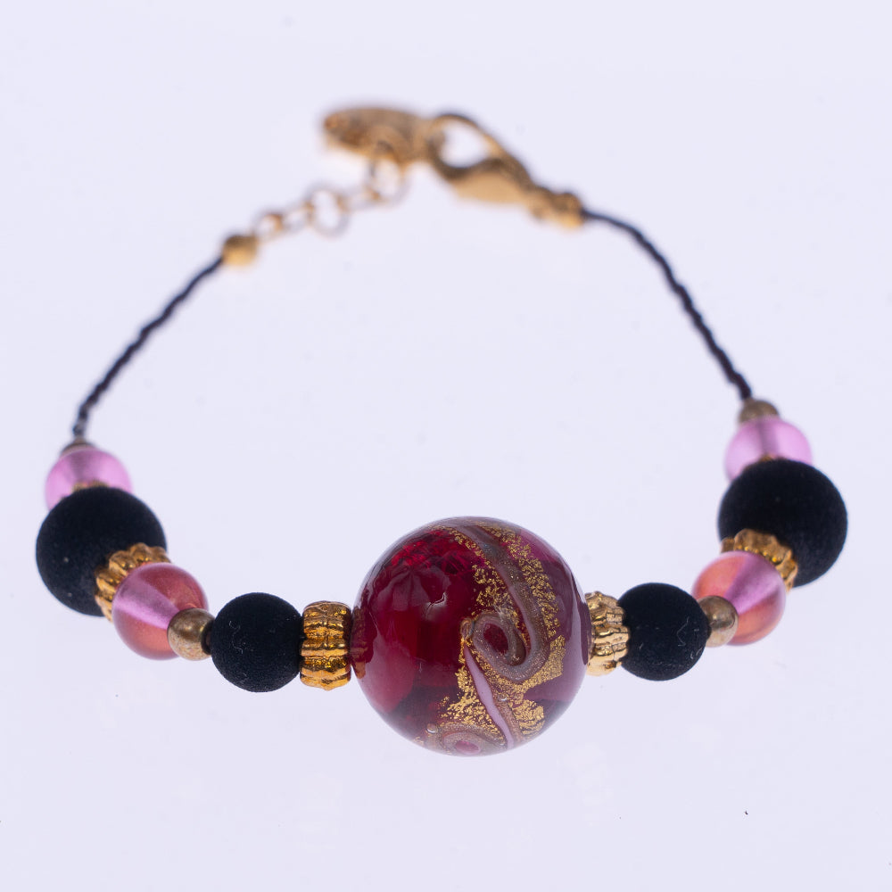 Dettaglio del bracciale di ungioielloperte.com con perla centrale in vetro di Murano rosa, perle in pietra lavica e dettagli in metallo dorato
