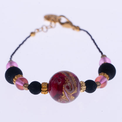 Dettaglio del bracciale di ungioielloperte.com con perla centrale in vetro di Murano rosa, perle in pietra lavica e dettagli in metallo dorato